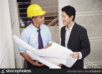 Side profile of a businessman and an architect holding blueprints