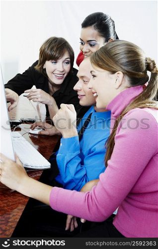 Side profile of a businessman and three businesswomen using a desktop PC