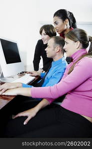 Side profile of a businessman and three businesswomen using a desktop PC