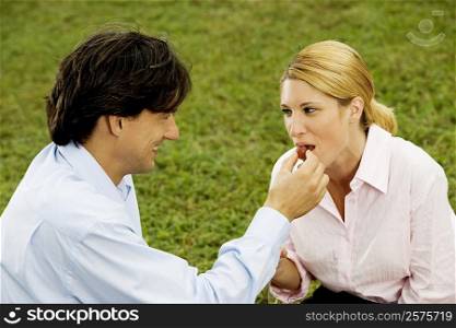 Side profile of a businessman feeding a cherry to a businesswoman