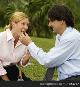 Side profile of a businessman feeding a cherry to a businesswoman