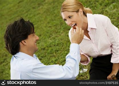 Side profile of a businessman feeding a cherry to a businesswoman