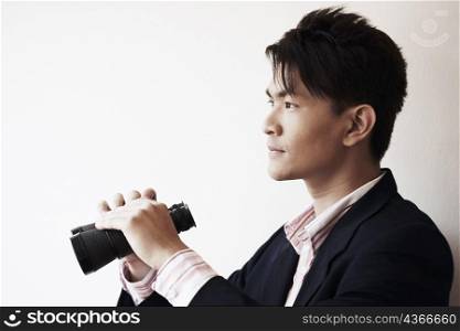 Side profile of a businessman holding a pair of binoculars