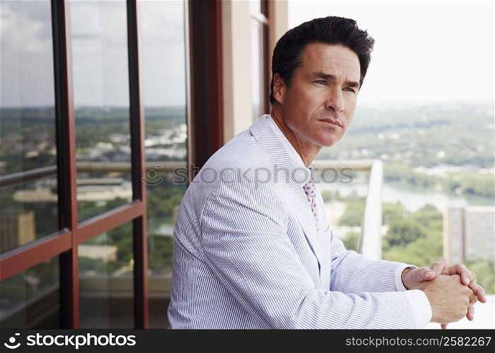 Side profile of a businessman leaning against a railing