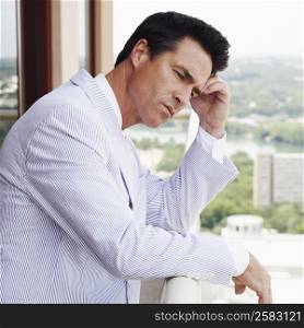 Side profile of a businessman leaning against a railing and thinking