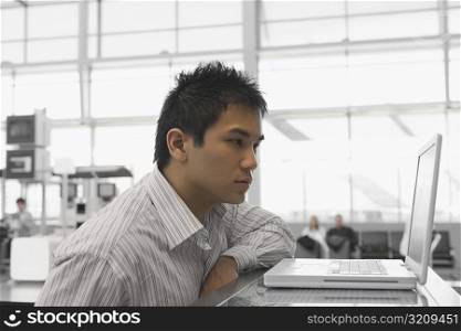 Side profile of a businessman looking at a laptop at an airport check-in counter