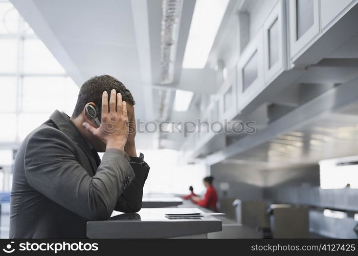 Side profile of a businessman looking serious at a ticket counter in an airport