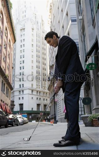 Side profile of a businessman playing golf on the road