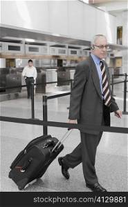Side profile of a businessman pulling his luggage
