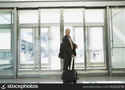 Side profile of a businessman pulling his luggage at an airport