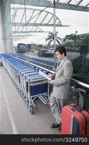Side profile of a businessman reading a document and waiting outside an airport