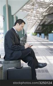 Side profile of a businessman sitting and using a hand held device