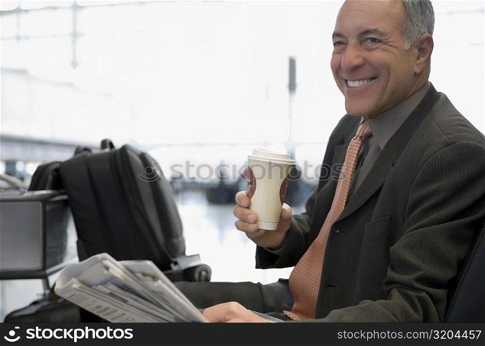 Side profile of a businessman sitting at an airport and smiling