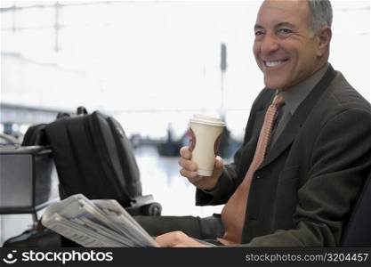 Side profile of a businessman sitting at an airport and smiling
