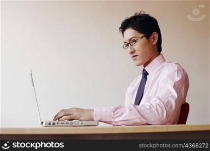 Side profile of a businessman sitting in an office and using a laptop