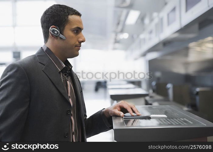 Side profile of a businessman standing at a ticket counter in an airport