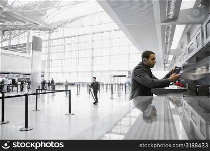 Side profile of a businessman standing at a ticket counter in an airport