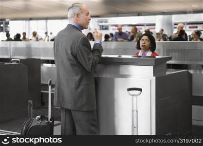 Side profile of a businessman standing at a ticket counter in an airport