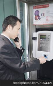 Side profile of a businessman talking on a public phone