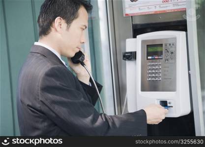 Side profile of a businessman talking on a public phone