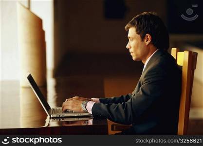 Side profile of a businessman typing on a laptop