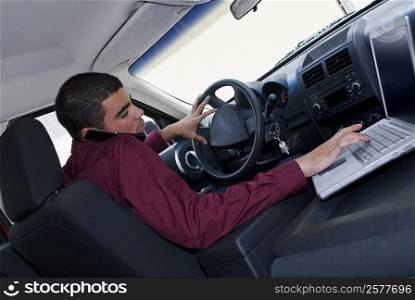 Side profile of a businessman using a laptop in a car