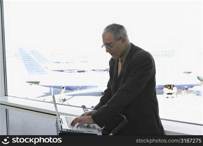 Side profile of a businessman using a laptop in the waiting room of an airport