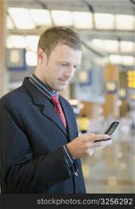 Side profile of a businessman using a mobile phone at an airport lounge