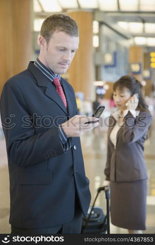 Side profile of a businessman using a mobile phone at an airport lounge