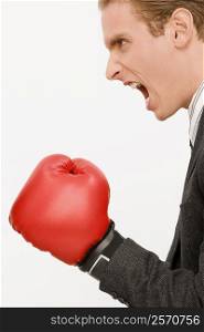 Side profile of a businessman wearing boxing gloves