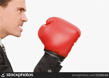 Side profile of a businessman wearing boxing gloves