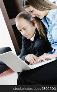 Side profile of a businessman with a teenage girl working on a laptop