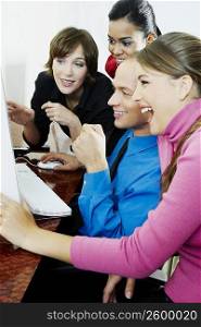 Side profile of a businessman with three businesswomen using a desktop PC