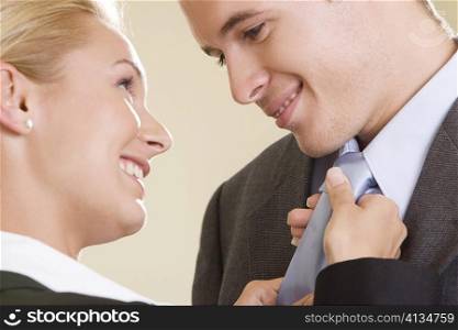 Side profile of a businesswoman adjusting a businessman&acute;s tie