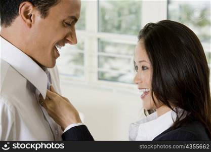 Side profile of a businesswoman adjusting businessman&acute;s tie