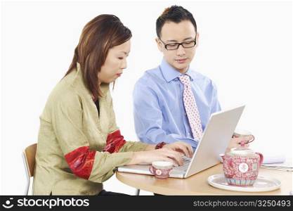 Side profile of a businesswoman and a businessman using a laptop