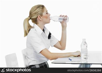 Side profile of a businesswoman drinking water from a water bottle