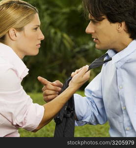 Side profile of a businesswoman holding a businessman&acute;s tie