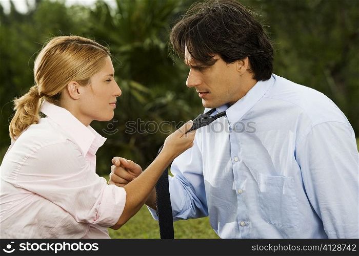Side profile of a businesswoman holding a businessman&acute;s tie