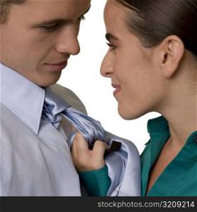 Side profile of a businesswoman holding a businessman by his tie