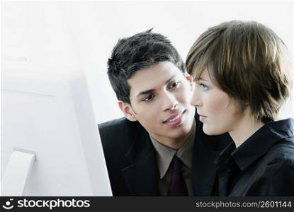 Side profile of a businesswoman looking at a computer monitor with a businessman looking at her
