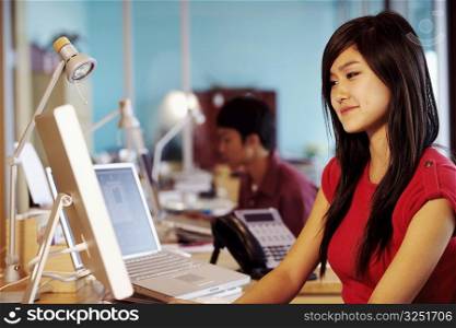Side profile of a businesswoman sitting in front of a computer in an office