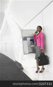 Side profile of a businesswoman talking on a pay phone at an airport