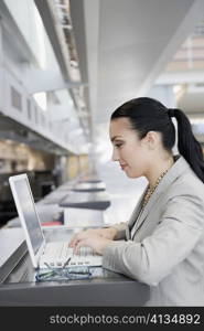 Side profile of a businesswoman using a laptop at an airport