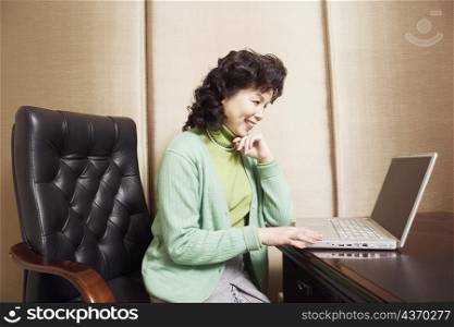 Side profile of a businesswoman using a laptop smiling
