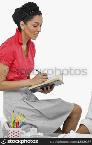 Side profile of a businesswoman writing on a notebook