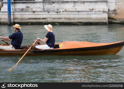 Side profile of a couple rowing a canoe, Venice, Veneto, Italy