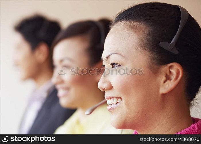 Side profile of a female customer service representative smiling with two colleagues