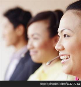 Side profile of a female customer service representative smiling with two colleagues