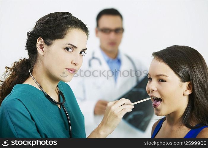 Side profile of a female doctor examining a girl&acute;s mouth with a tongue depressor